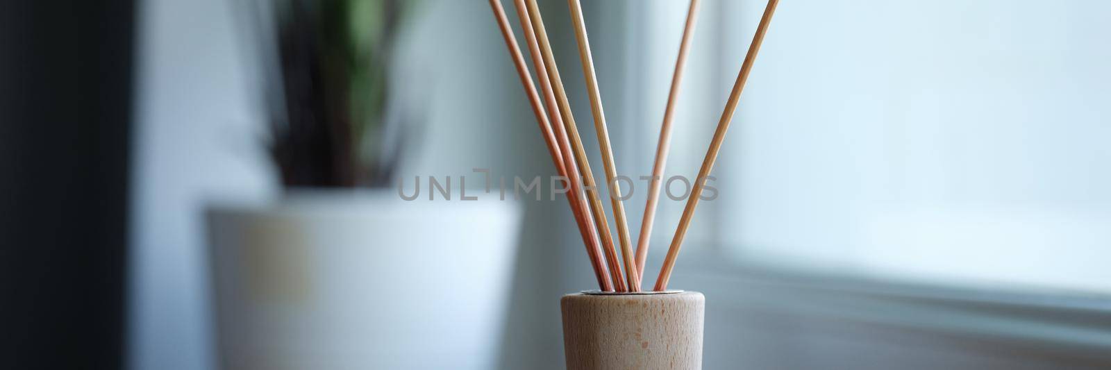 Wooden stick standing in jar with aromatic oils in apartment closeup. Sale of air fresheners concept