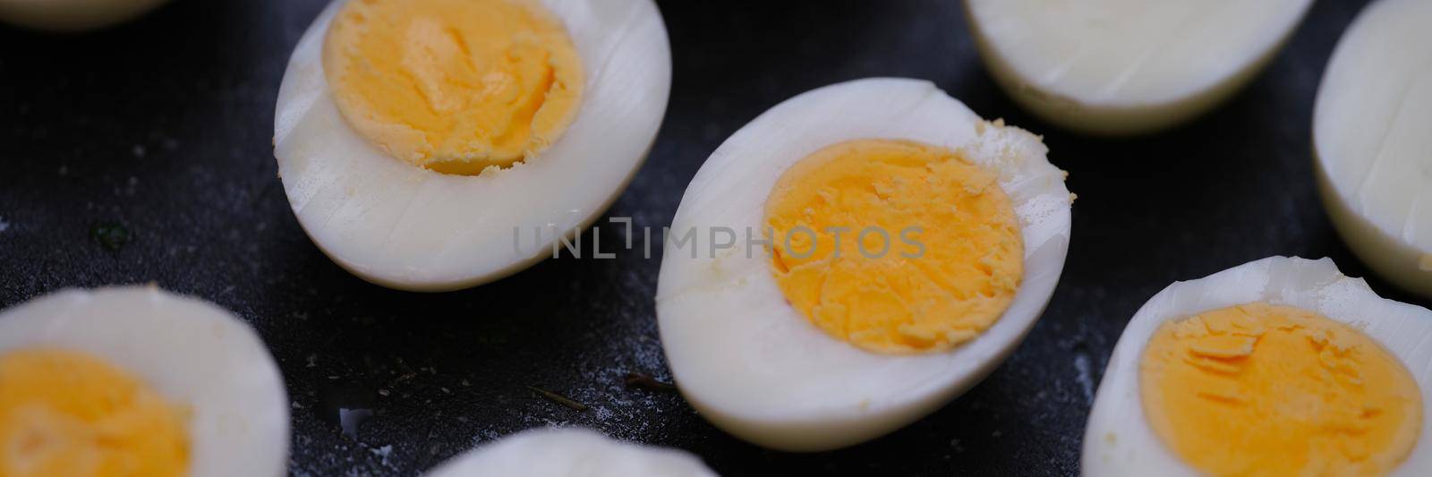 Many halves of boiled chicken eggs lying on table closeup background by kuprevich