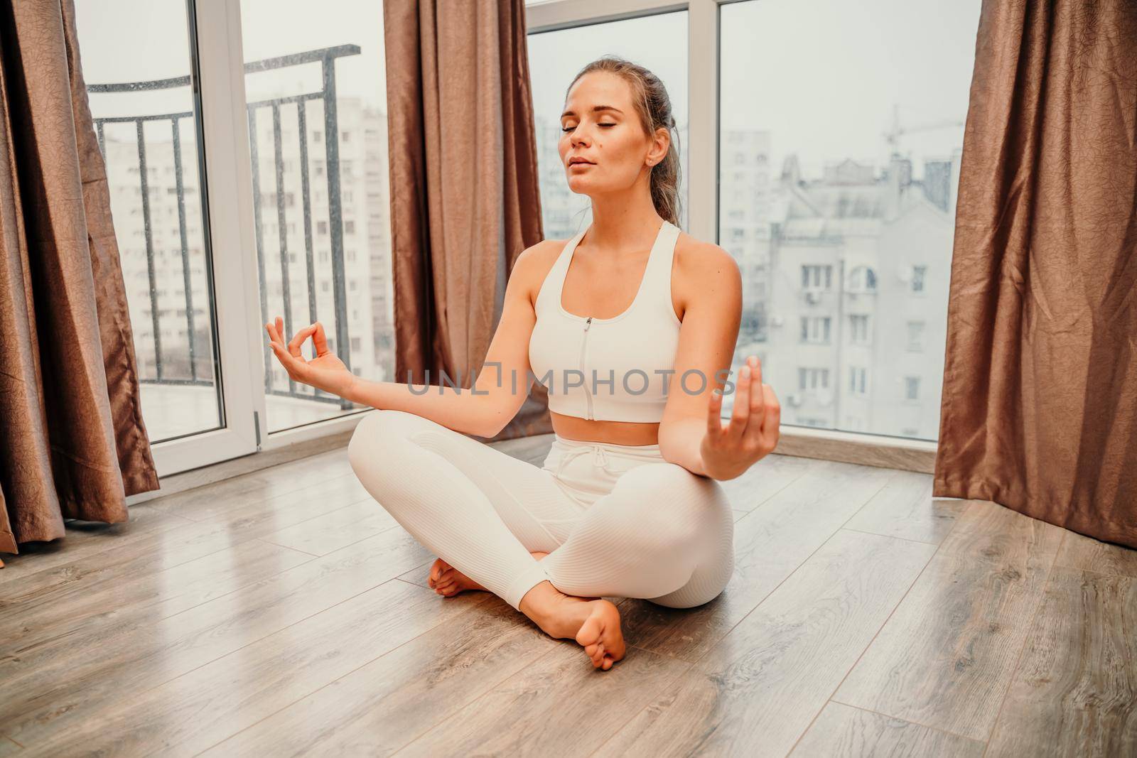 Young woman meditating at home. Girl practicing yoga in class. Relaxation at home, body care, balance, healthy lifestyle, meditation, mindfulness, recreation, workout, fitness, training concept.