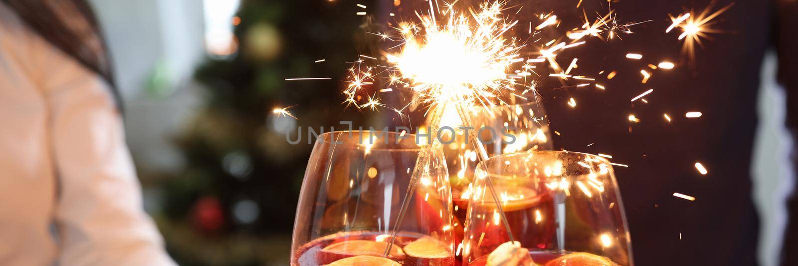 Three glasses with cocktails and sparklers on background of New Year tree by kuprevich