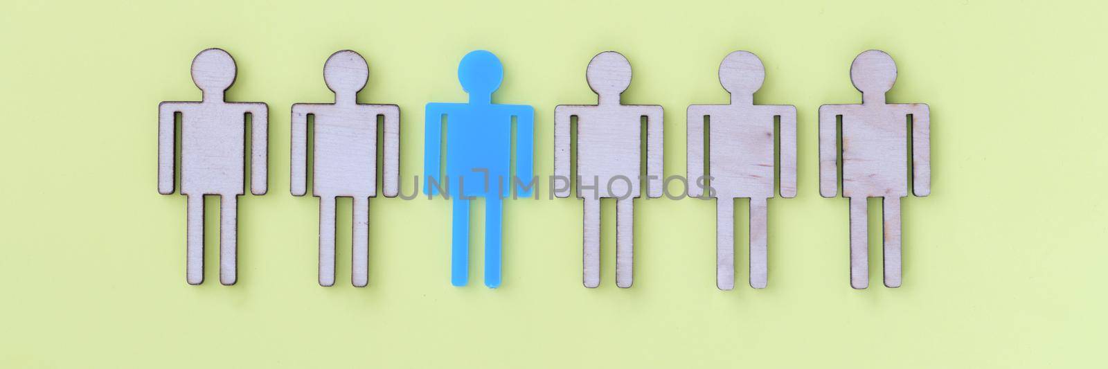 Figures of beige wooden little men in middle one blu by kuprevich