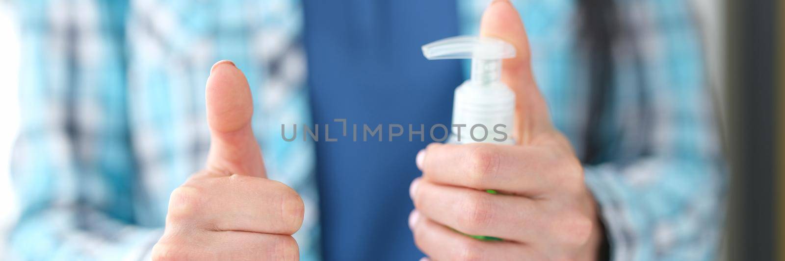 Woman holding disinfectant gesture thumbs up. Approved hand hygiene products concept