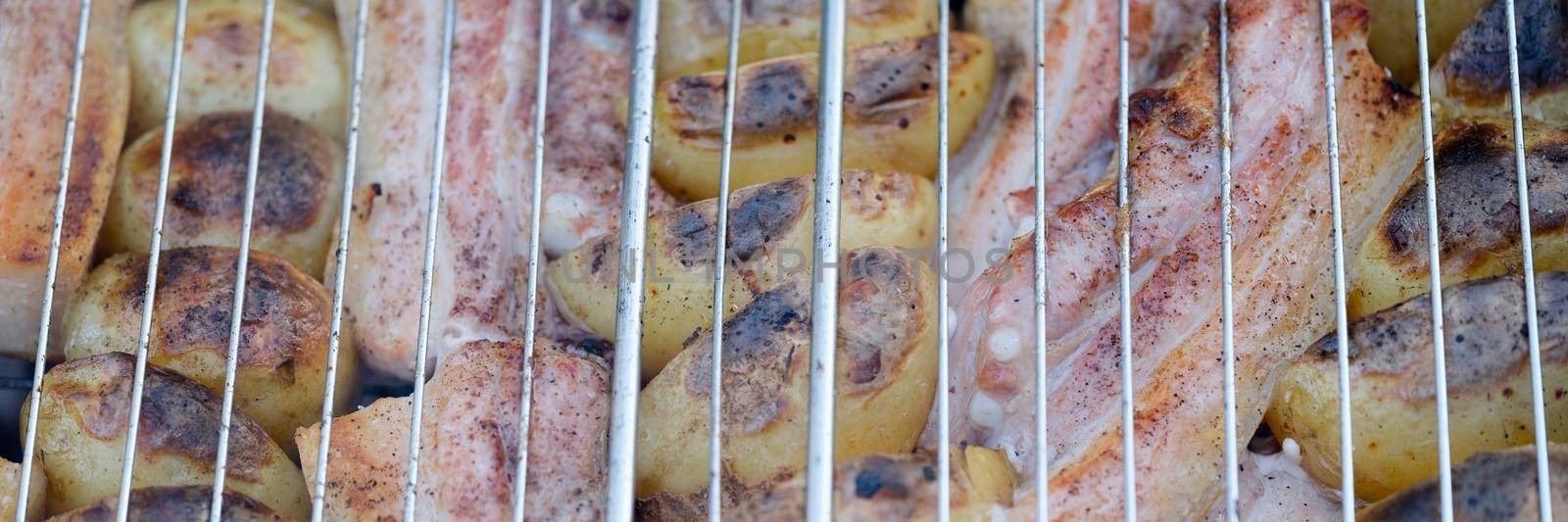 Grill potatoes and meat on wire rack closeup by kuprevich