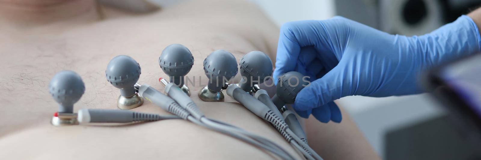 Nurse attaching suction cups to patient chest to record electrocardiogram closeup. ECG diagnostics of rhythm and conduction disorders concept
