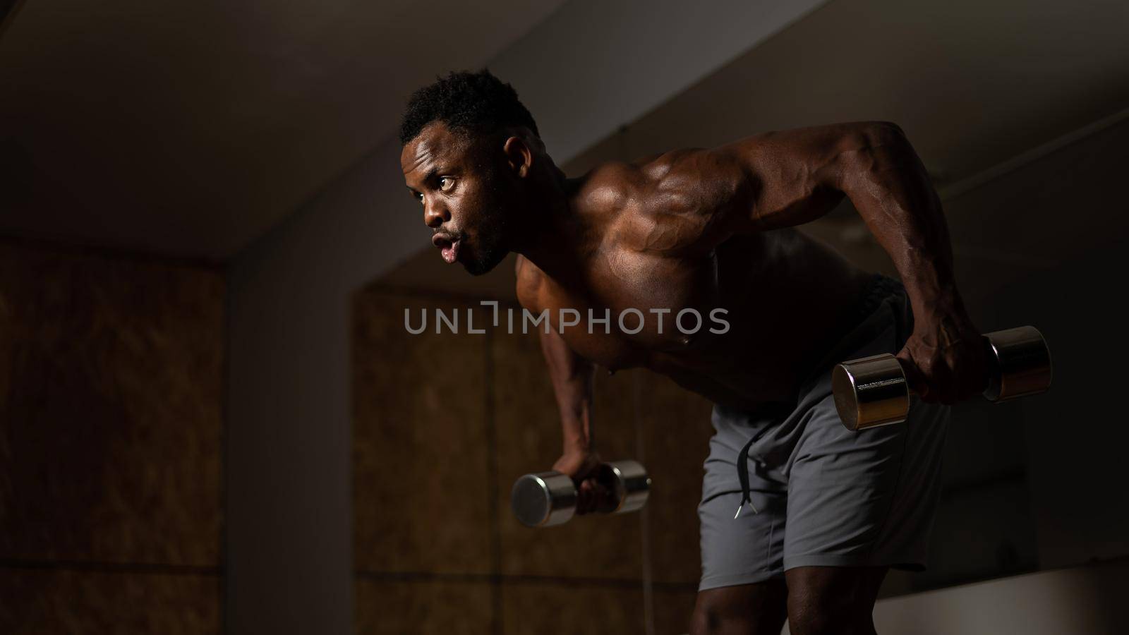 Attractive african american man doing arm exercises with dumbbells. by mrwed54