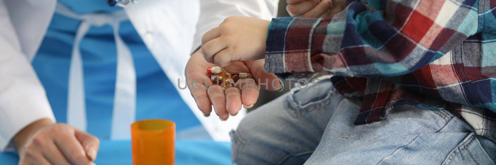 Little boy and doctor folding medical capsules in jar closeup by kuprevich