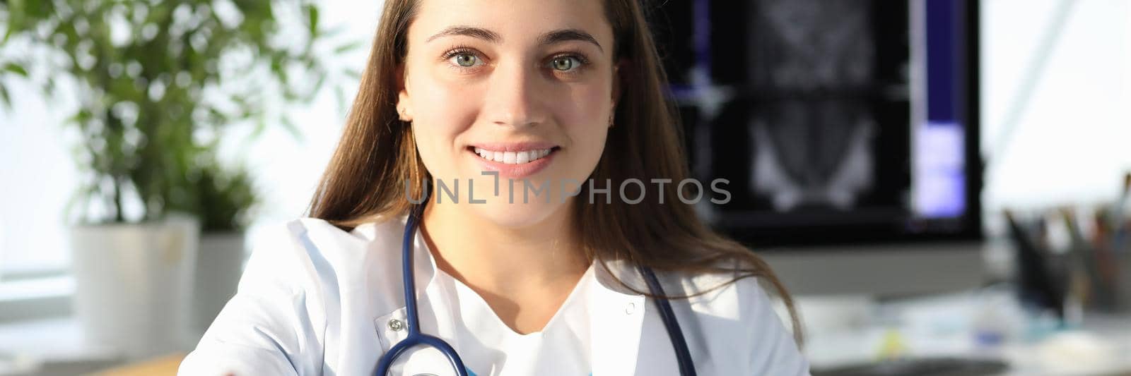 Woman doctor giving hand for handshake in clinic. Professional medical consultation concept