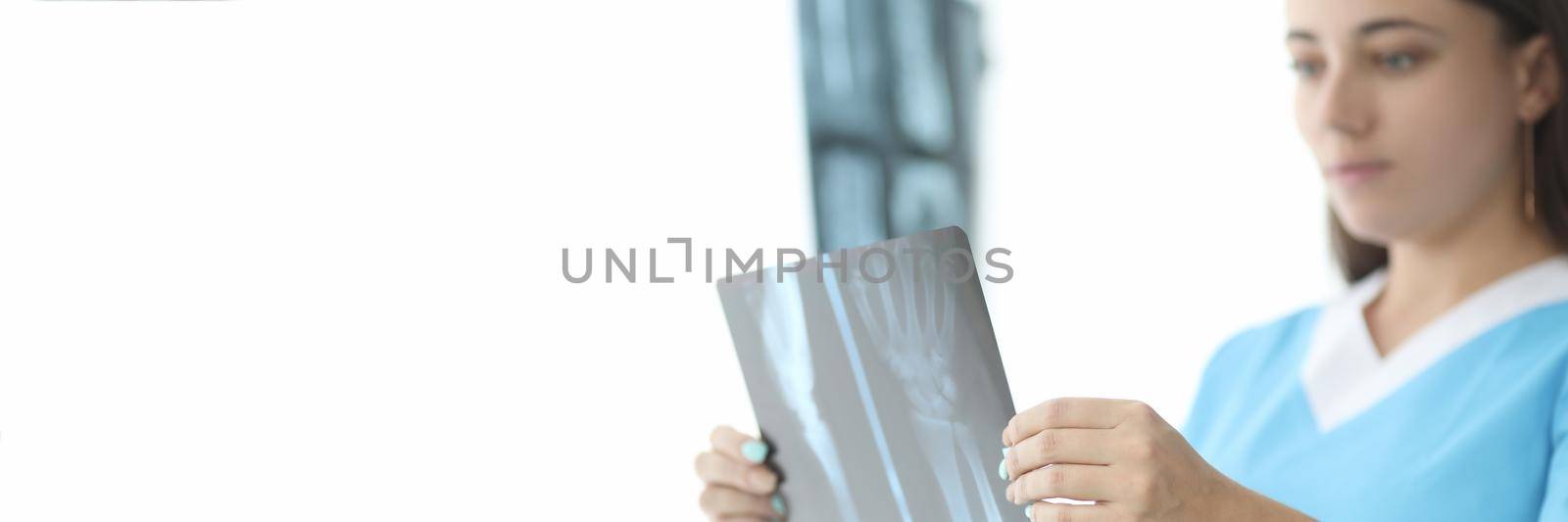 Traumatologist doctor looking at xray of hand in clinic closeup by kuprevich