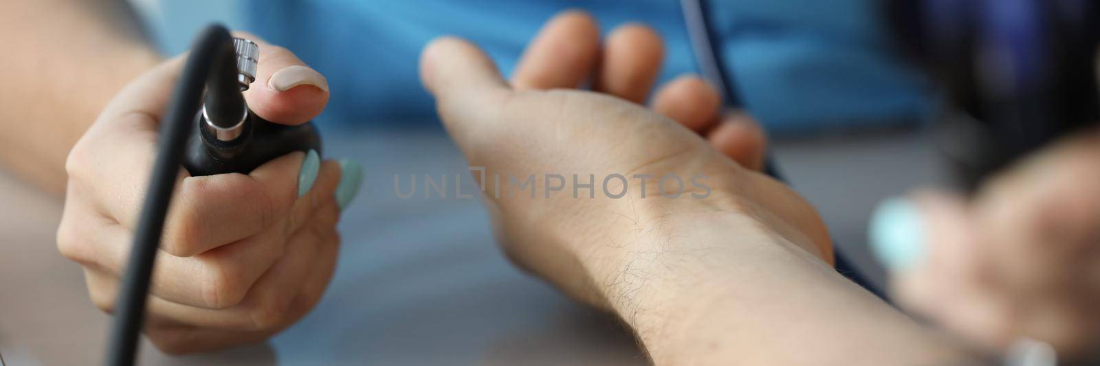 Cardiologist measuring blood pressure to patient in clinic closeup. Principles of arterial hypertension treatment concept