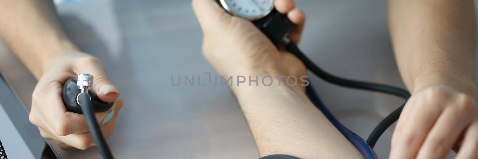 Doctor measuring patient blood pressure on arm using tonometer closeup. Diagnosis and treatment of arterial hypertension concept