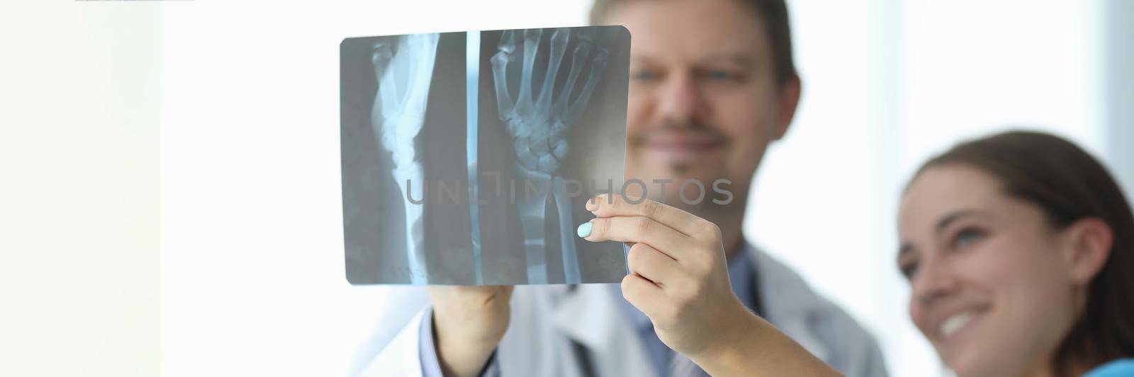 Doctors looking at xray of hand in clinic closeup. X ray diagnosis of arthritis concept