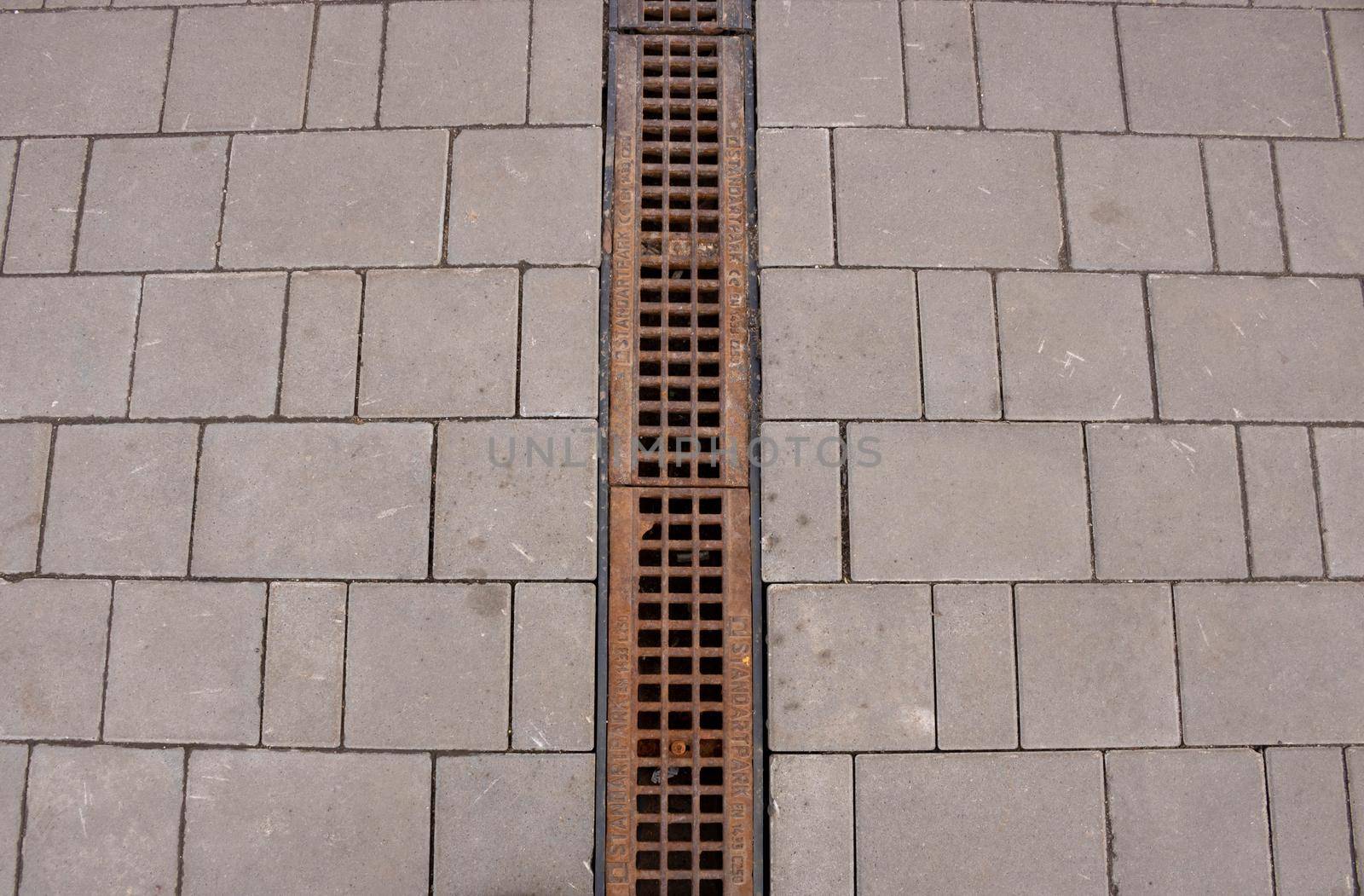 An old rusty drainage grate on a granite sidewalk by lapushka62