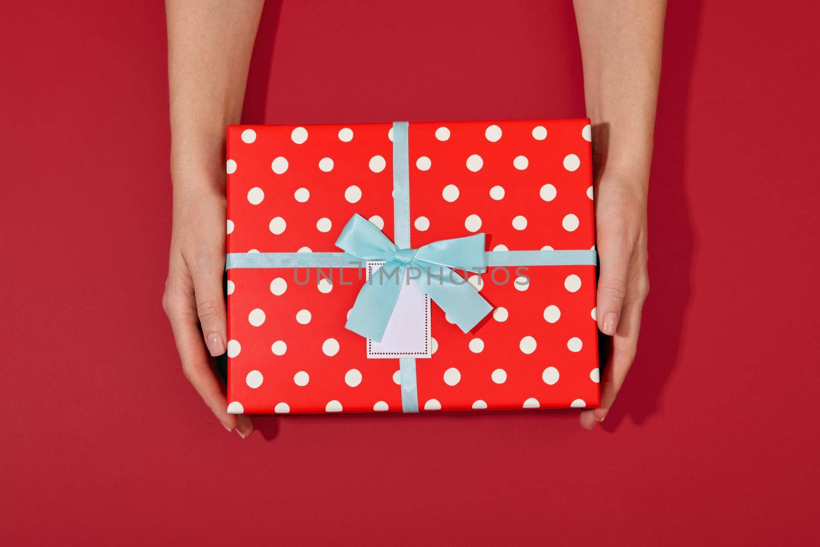 Hands holding gift box turquoise red background by Demkat