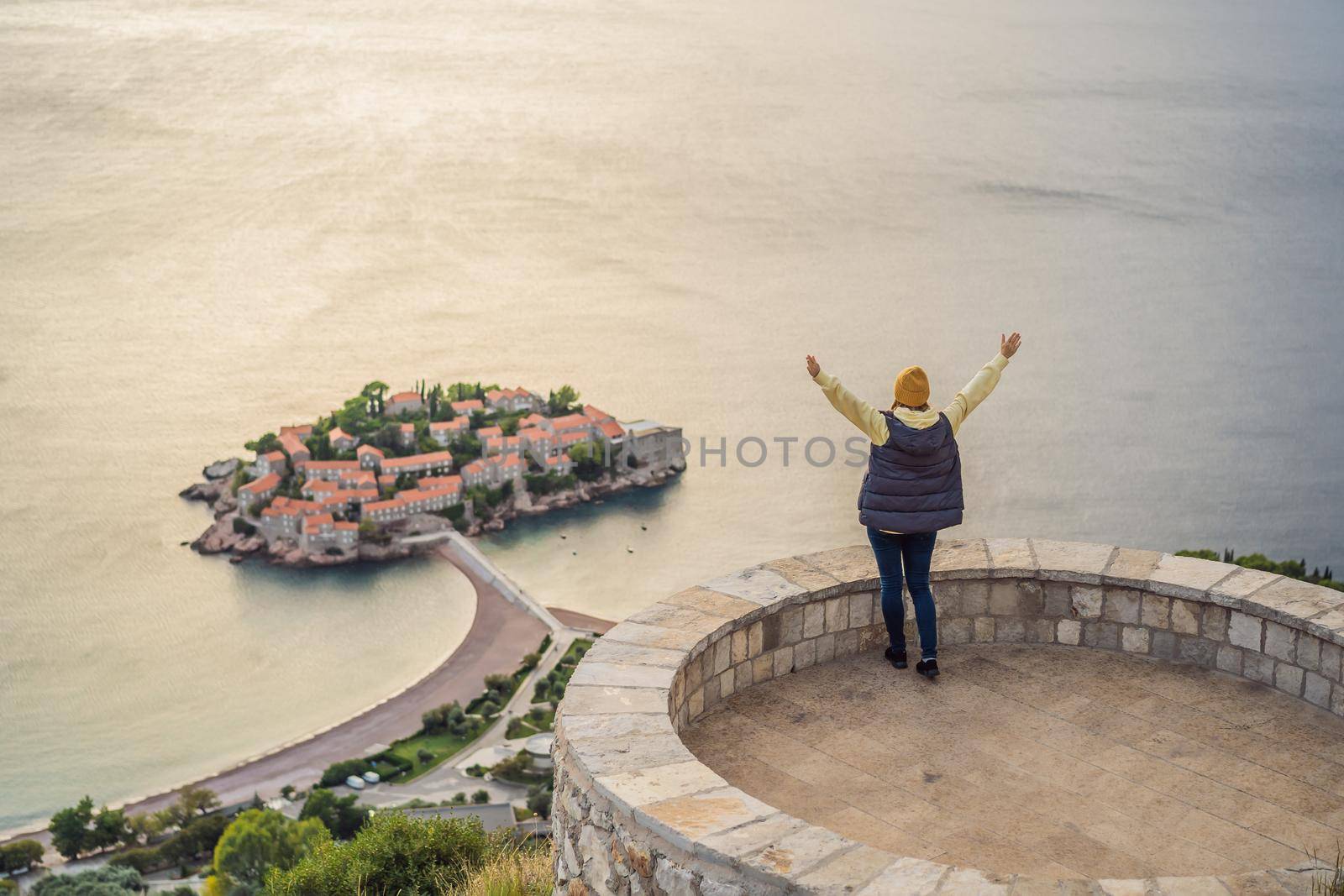 Woman tourist on background of beautiful view of the island of St. Stephen, Sveti Stefan on the Budva Riviera, Budva, Montenegro. Travel to Montenegro concept.