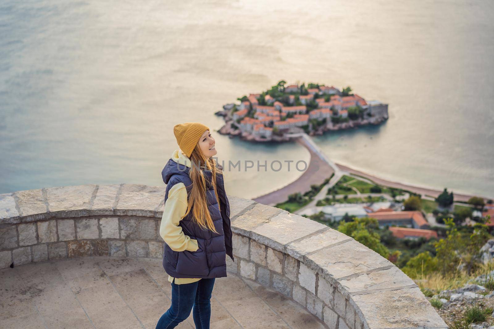 Woman tourist on background of beautiful view of the island of St. Stephen, Sveti Stefan on the Budva Riviera, Budva, Montenegro. Travel to Montenegro concept.