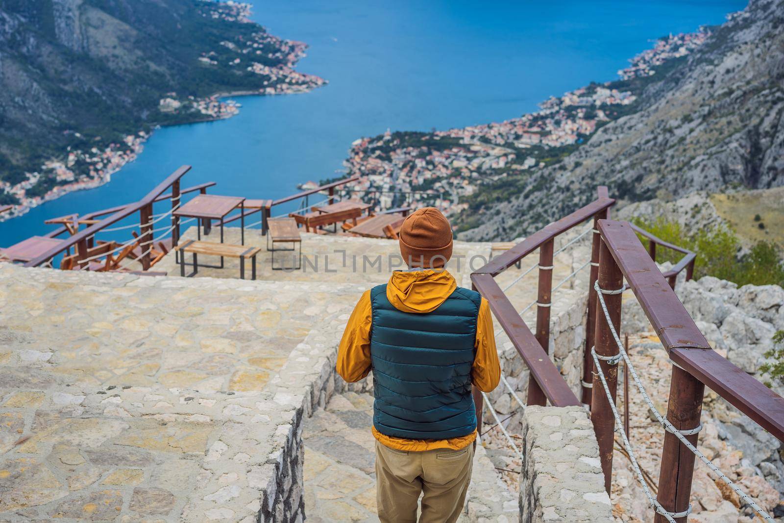 Man tourist enjoys the view of Kotor. Montenegro. Bay of Kotor, Gulf of Kotor, Boka Kotorska and walled old city. Travel to Montenegro concept. Fortifications of Kotor is on UNESCO World Heritage List since 1979.