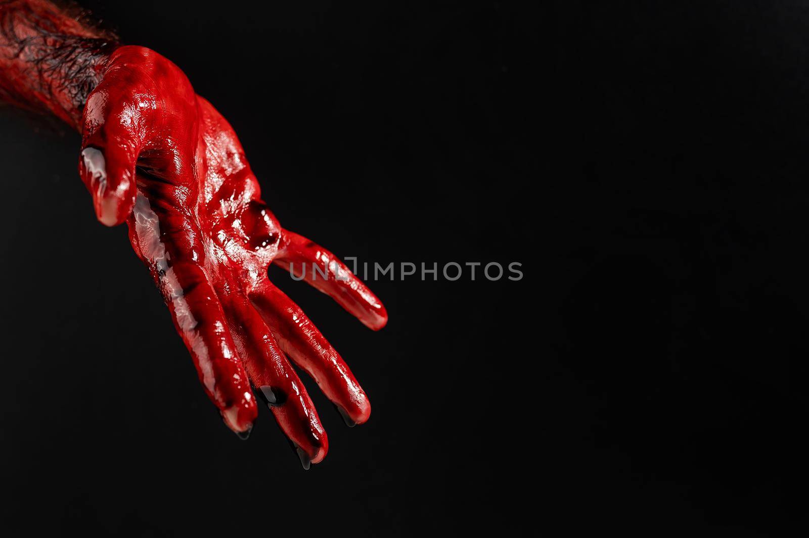 Close-up of a male hand stained with blood on a black background