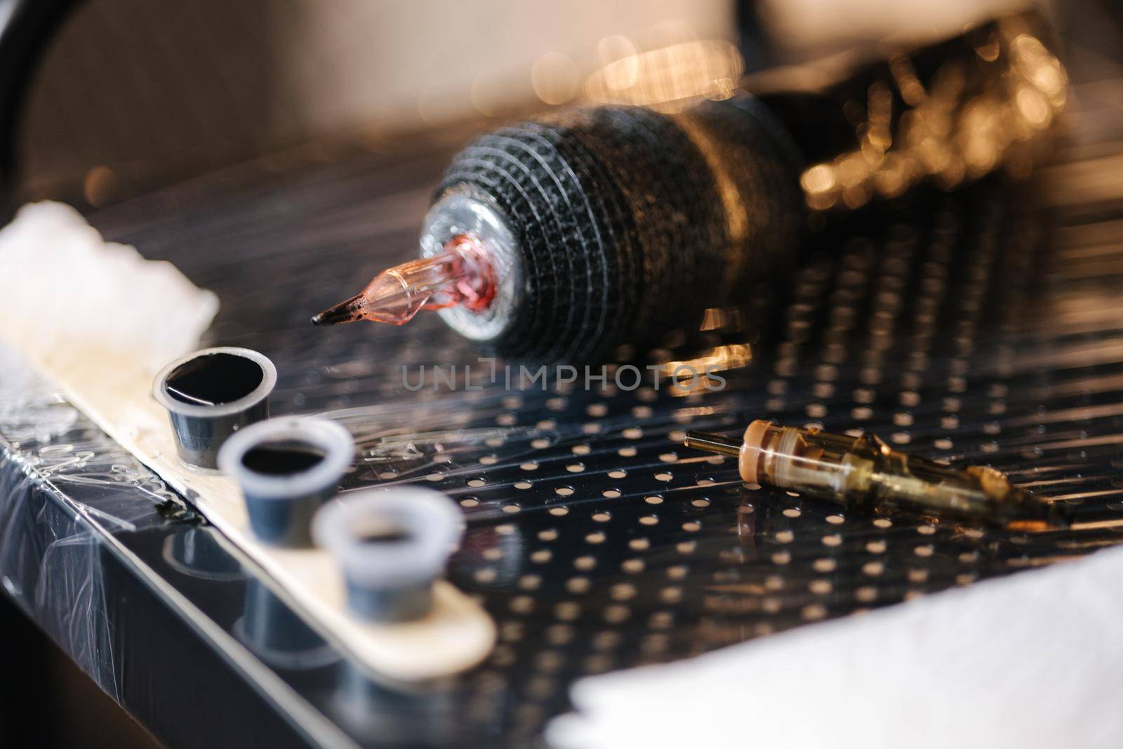 Close-up of tattoo machine in studio. Professionnal wireless tatto machine and little cups with ink.