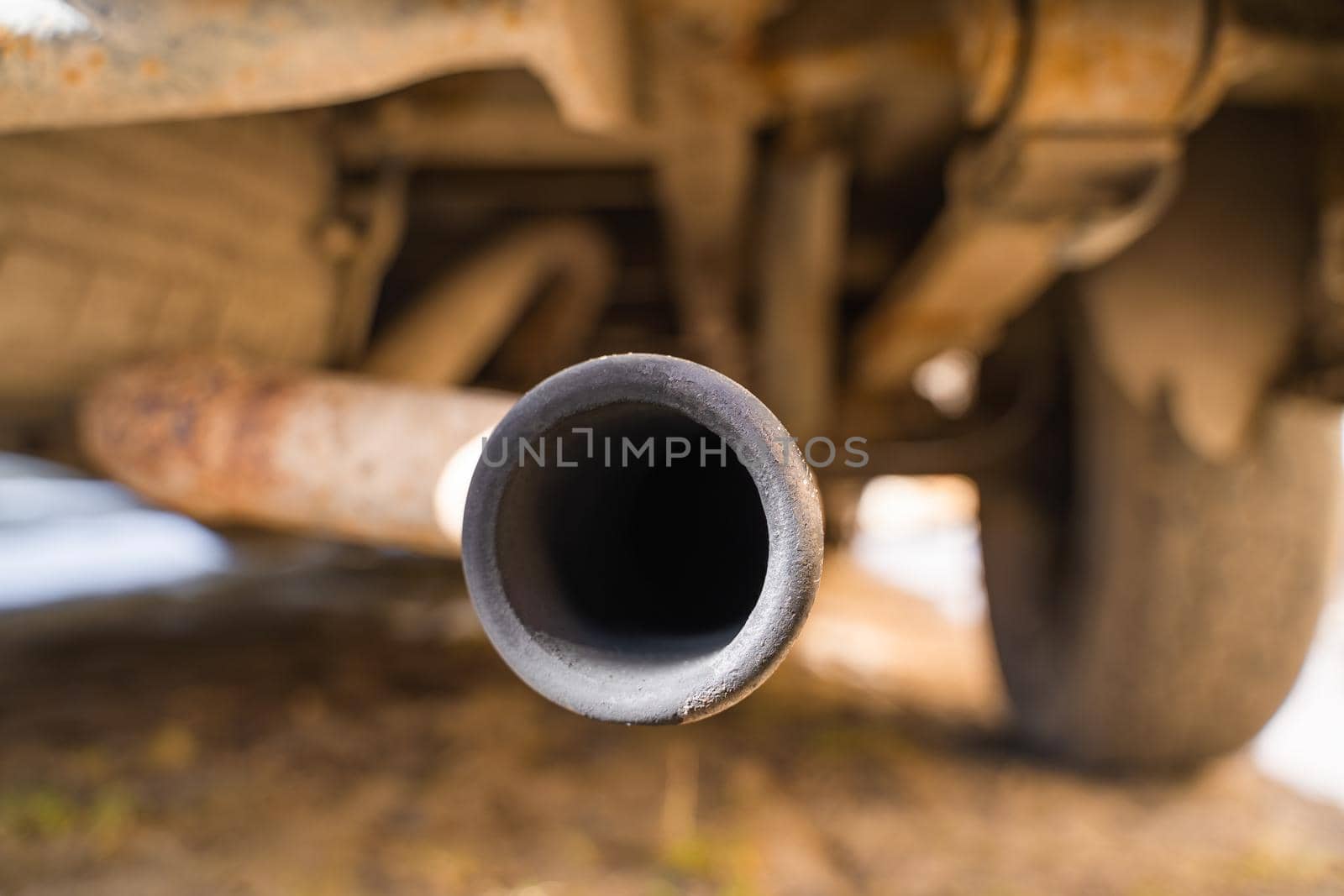 Rusty exhaust pipe with soot close-up. The spare tire is installed from below, the bottom of the car