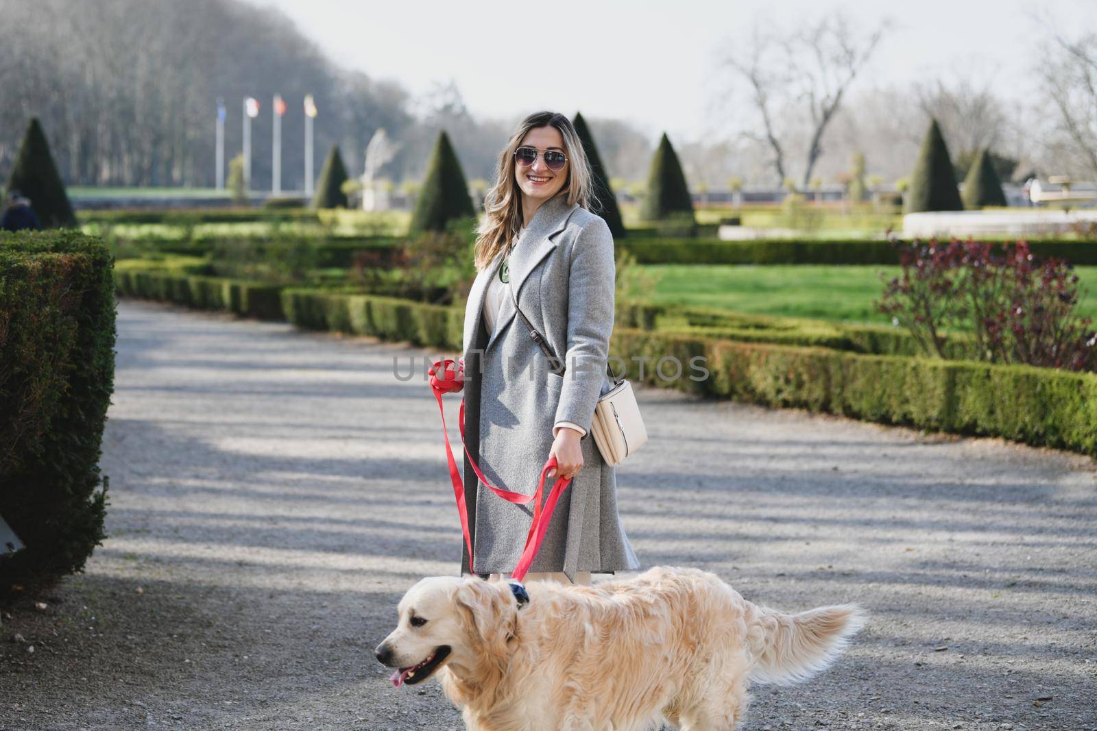 Stylish woman walking with a labrador on a leash in a park