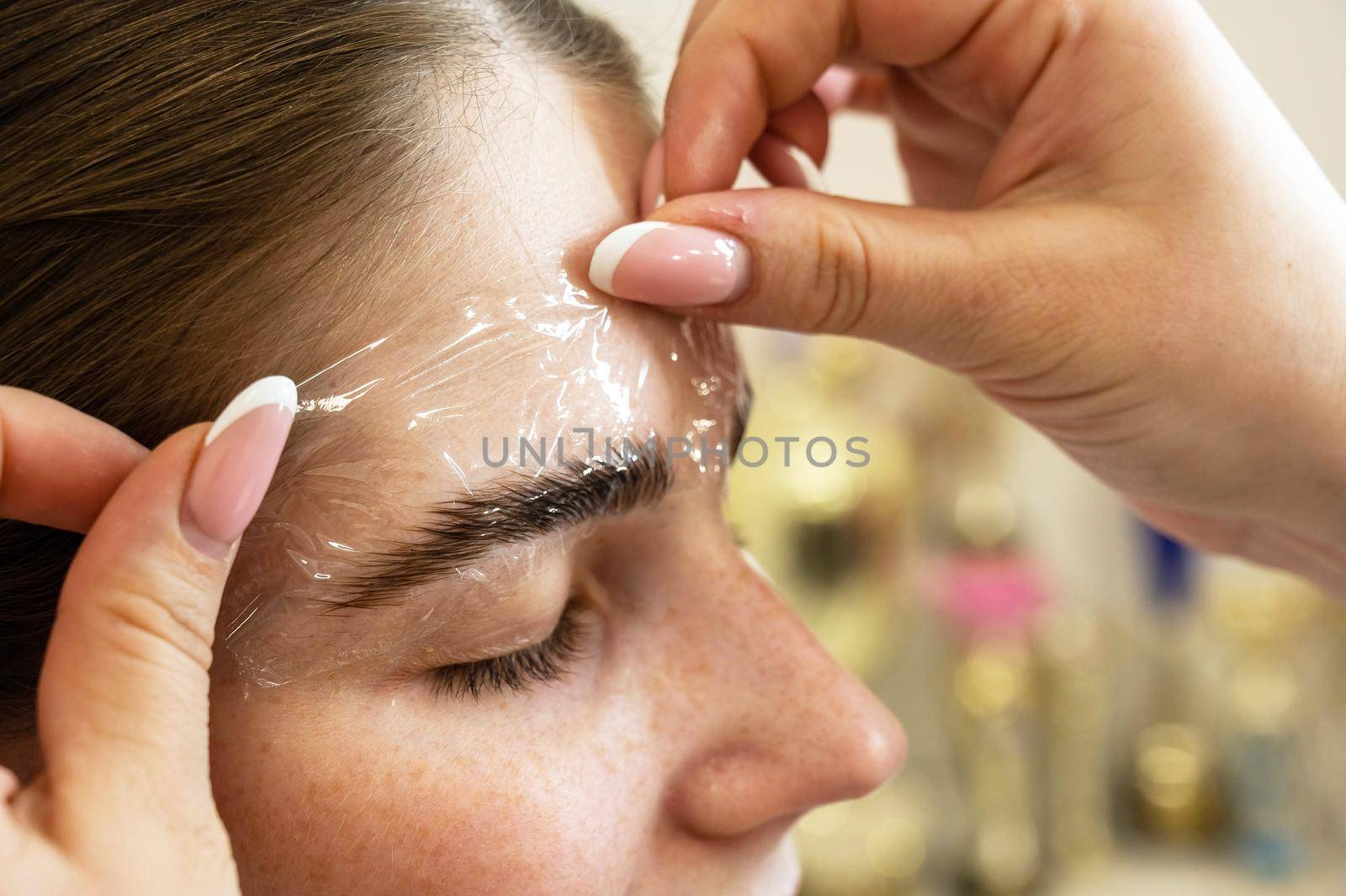 The master uses a plastic film during lamination of the eyebrows