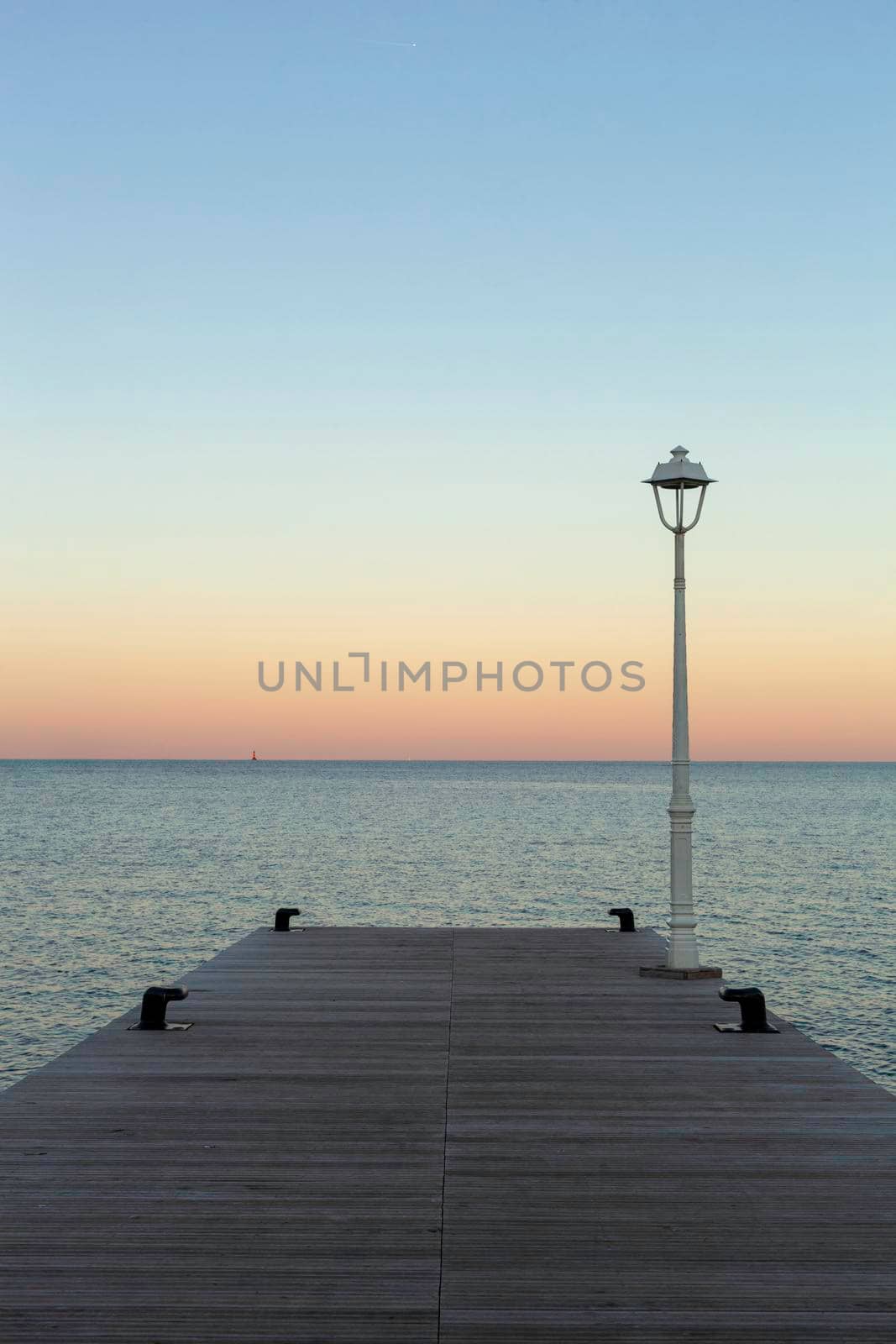 wooden pier with a lantern, sunset on the sea, copy space