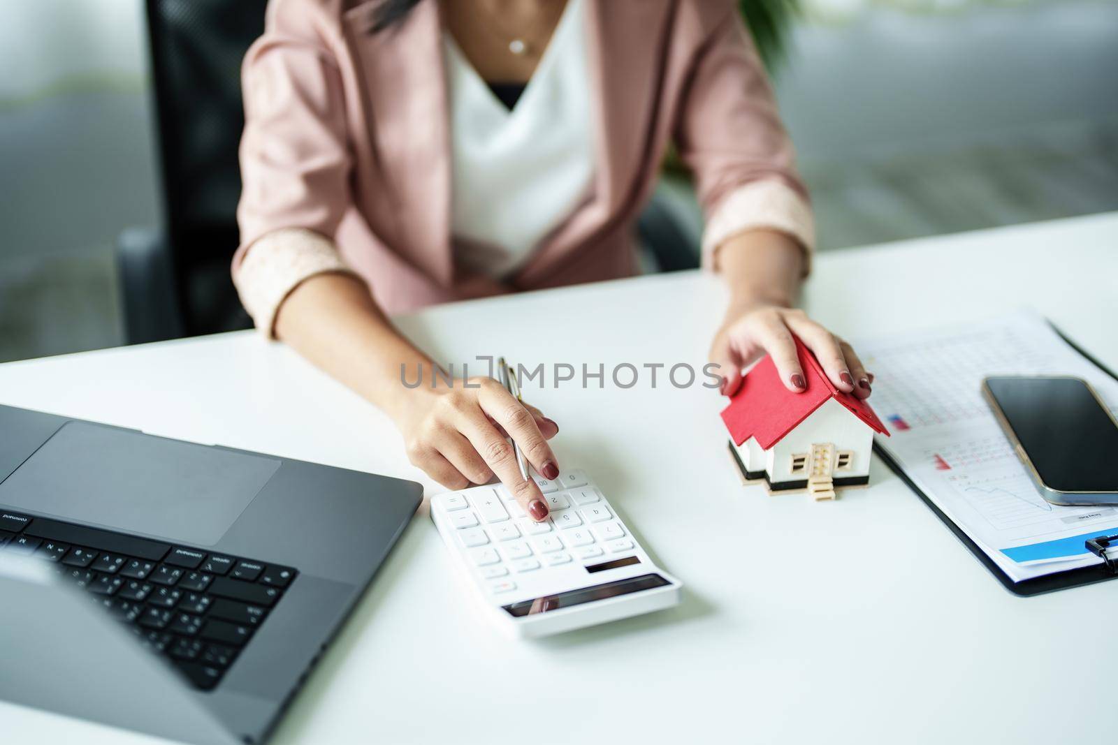 Entrepreneurs, business owners, accountants, real estate agents, A young woman uses a calculator to calculate her home budget to assess the risks of investing in real estate. by Manastrong