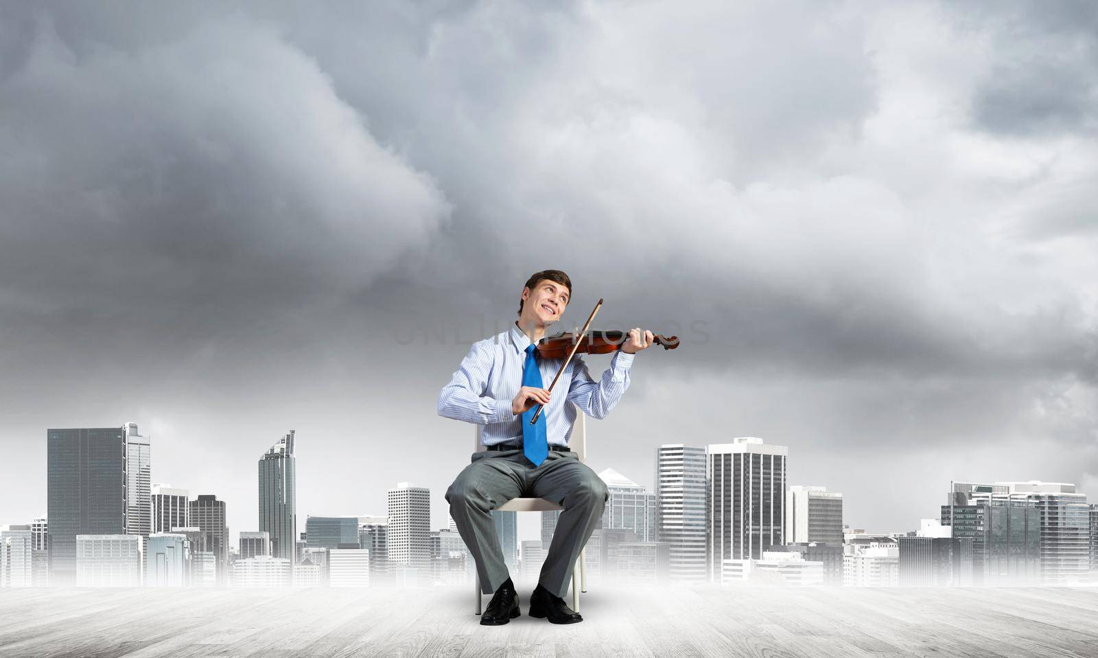 young businessman sits on a chair and plays the violin. the concept of creativity and inspiration in business