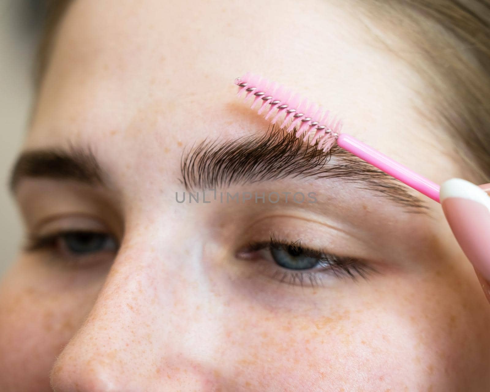 Close-up portrait caucasian woman combing her eyebrows. by mrwed54