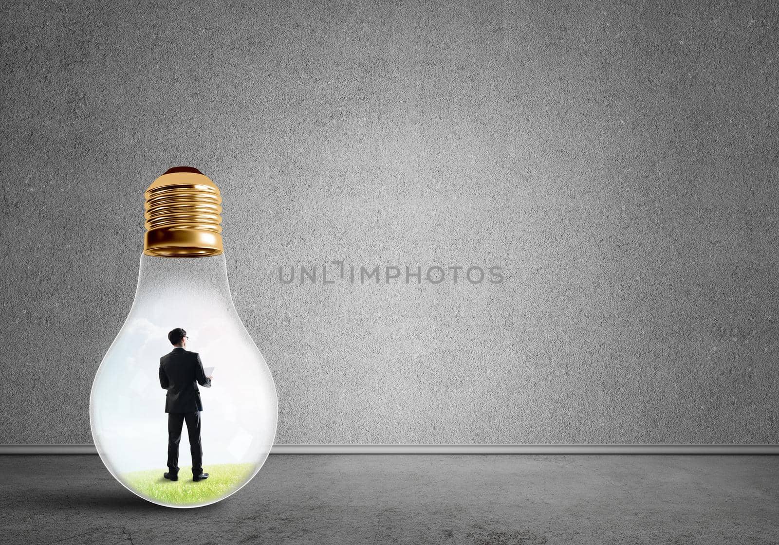 Businessman inside of light bulb in empty concrete room