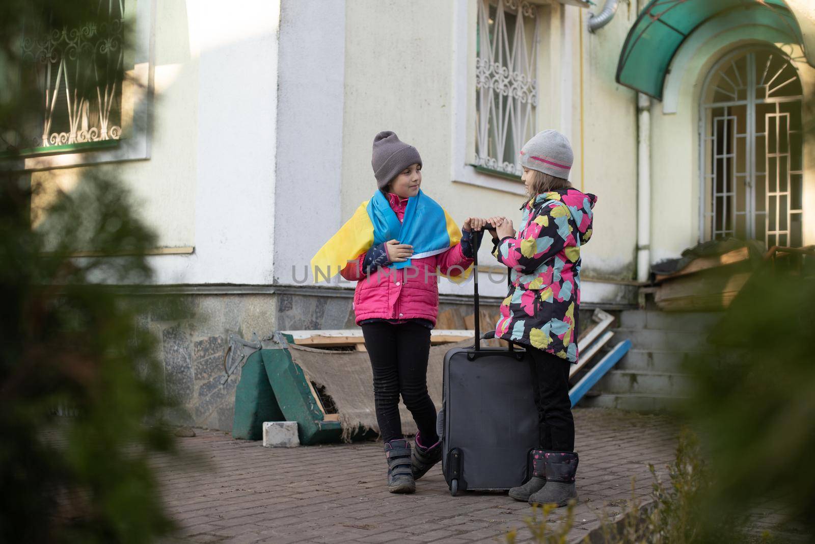 Ukraine military migration. two little girls with a suitcase. Flag of Ukraine, help. Crisis, military conflict.