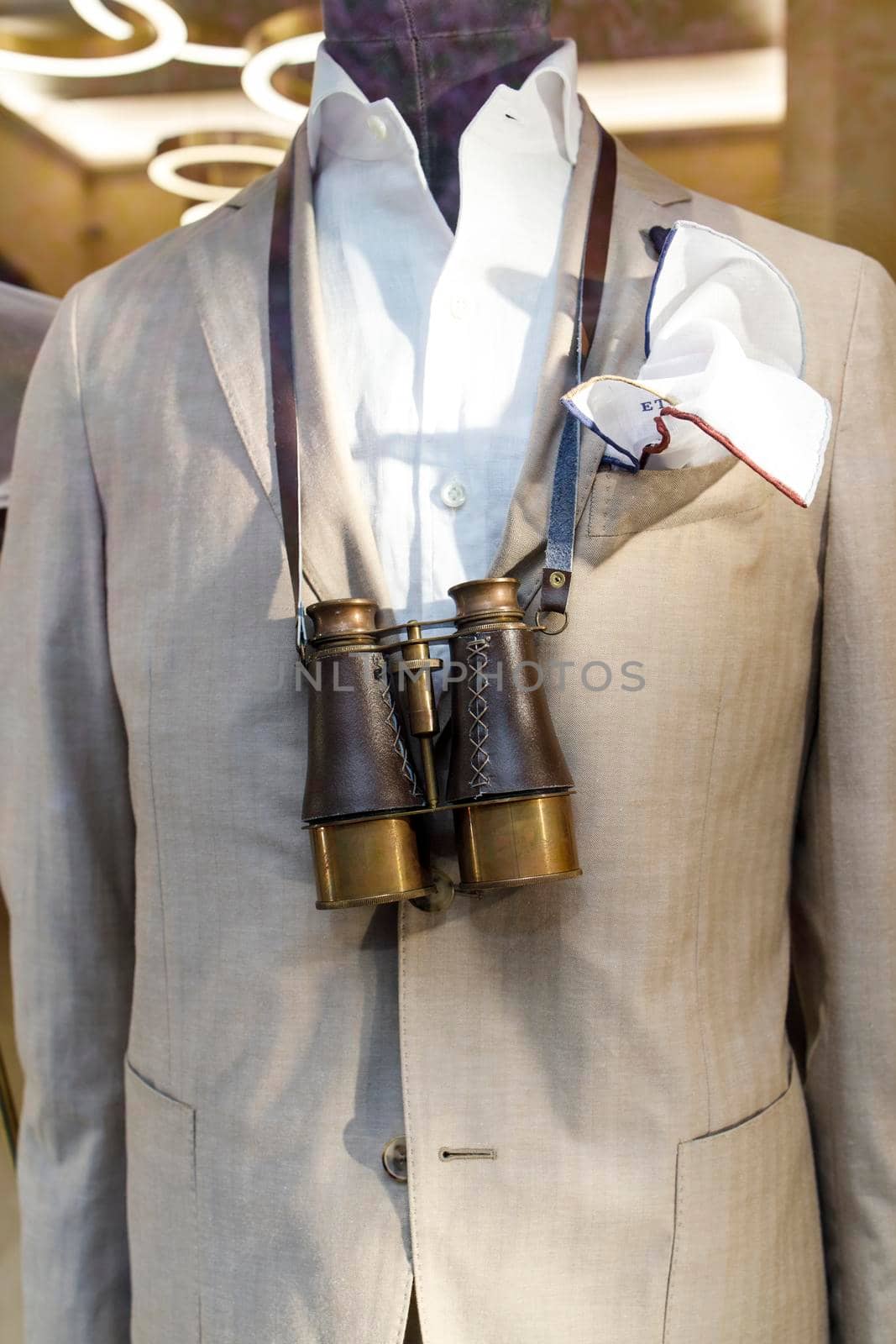 A fragment of a beige jacket and large vintage binoculars on the chest of a mannequin by elenarostunova