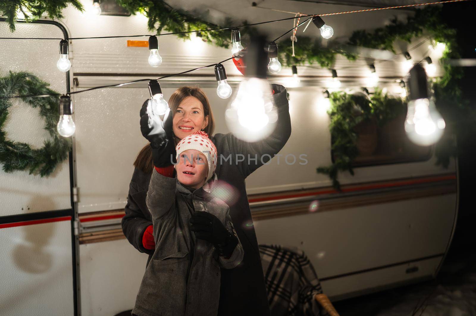 Caucasian woman and son decorate camper for christmas. Happy family travels in a mobile home. by mrwed54
