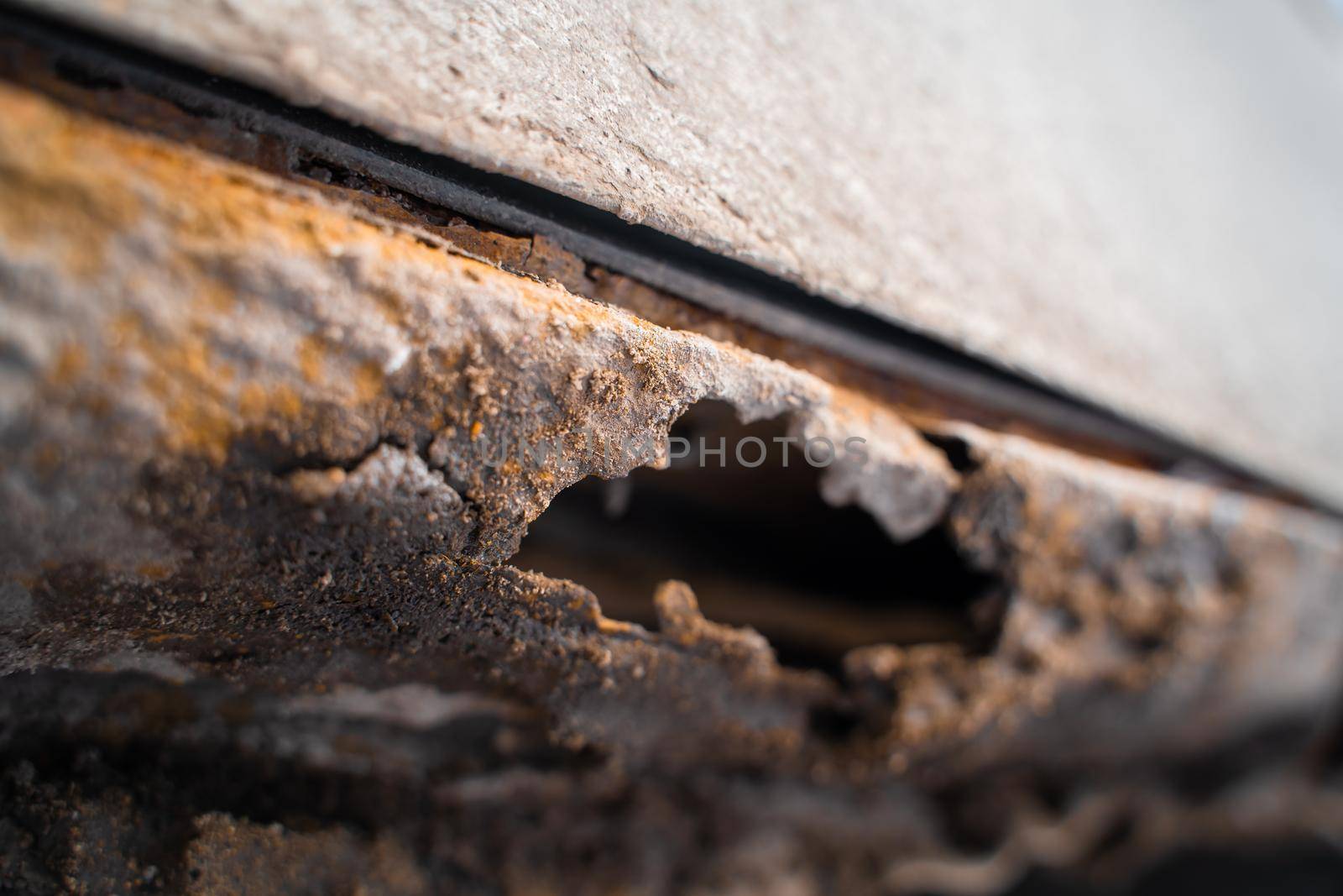 Rusted white car sills close-up. The effect of reagents in winter on an unprotected car body