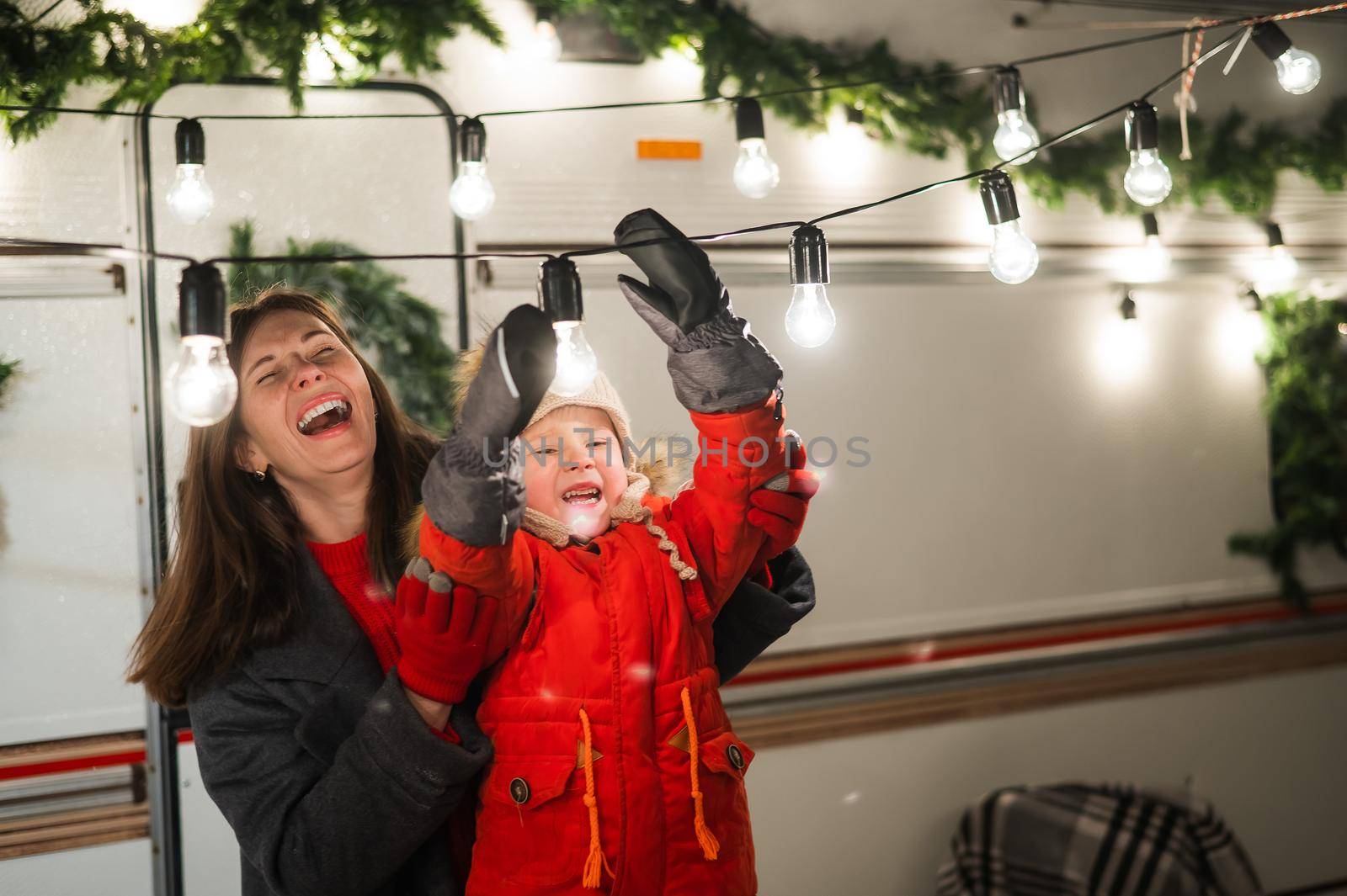 Caucasian woman and son decorate camper for christmas. Happy family travels in a mobile home
