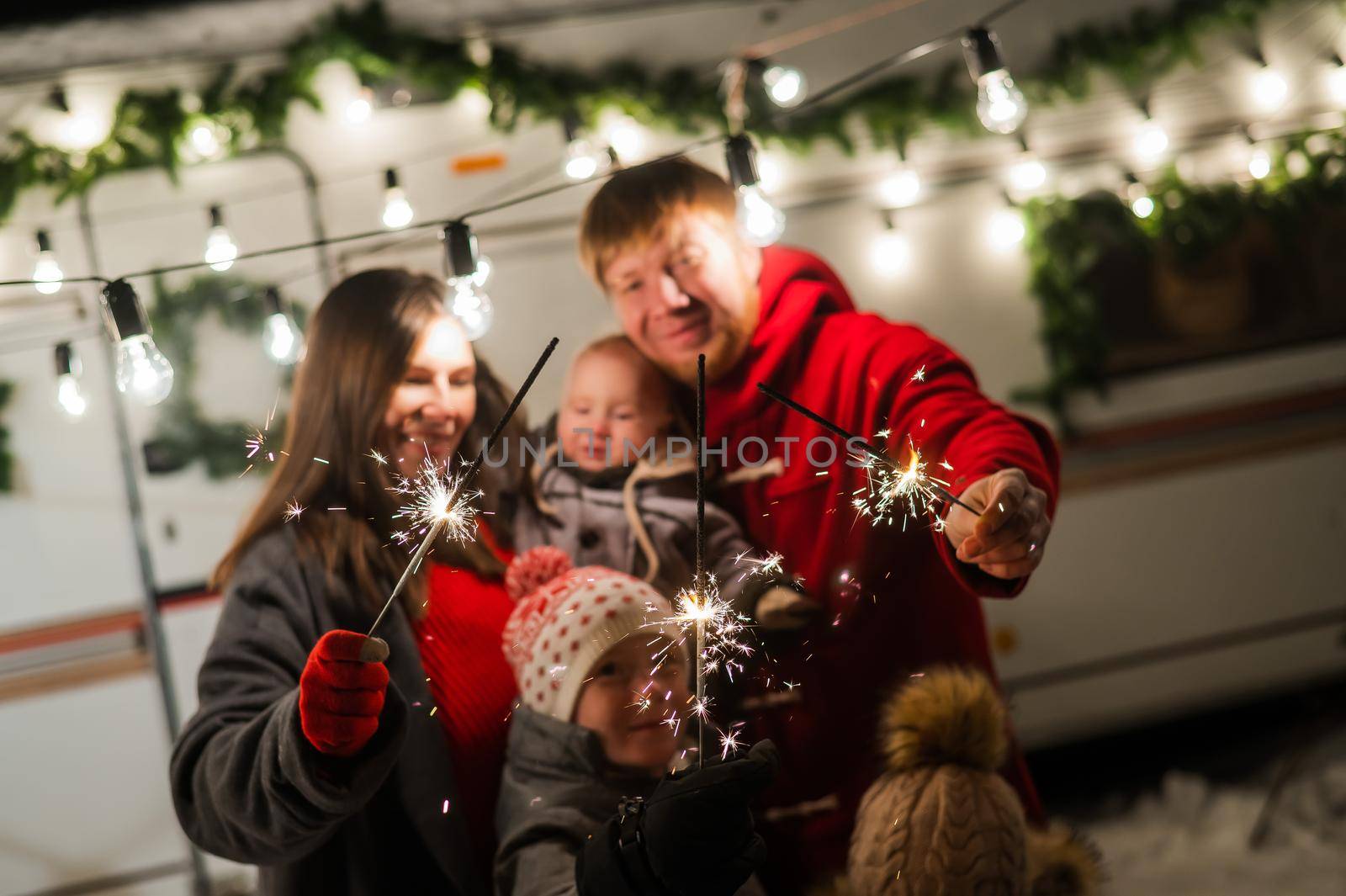 Happy large family celebrates christmas in nature and holds sparklers. Parents with three sons travels in a mobile home. by mrwed54