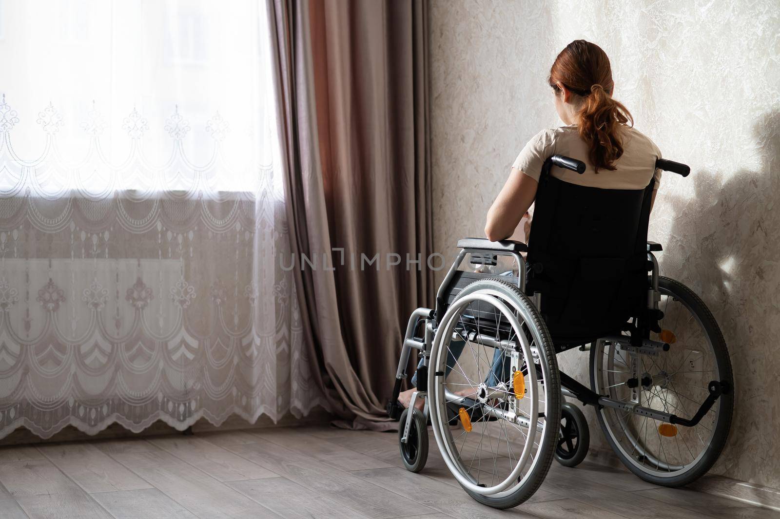Caucasian woman in a wheelchair at the window