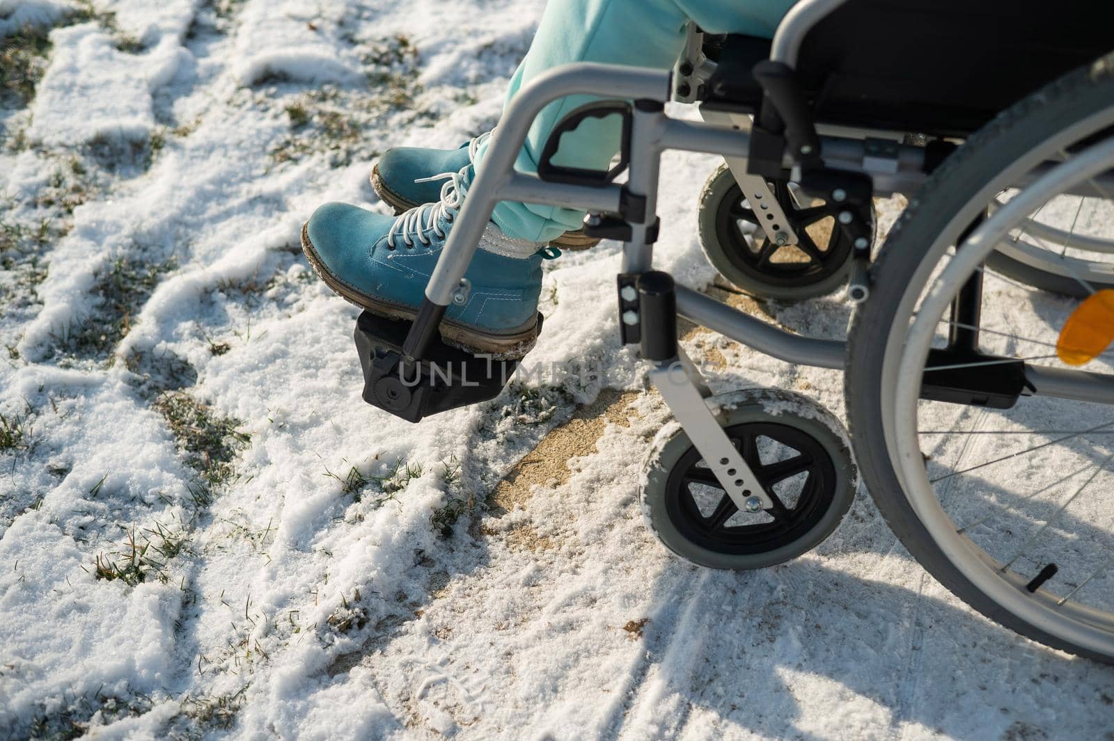 Close-up of legs of woman in wheelchair in winter outdoors. by mrwed54