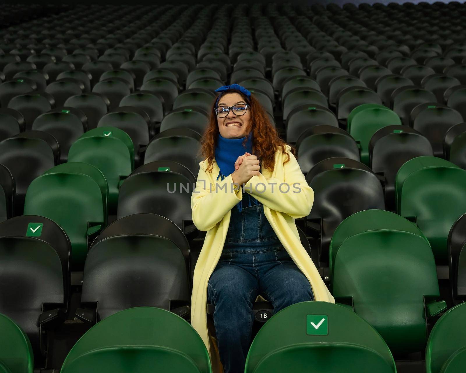 Caucasian woman cheers for a sports team at the stadium. The girl watches the match at the stadium alone. by mrwed54