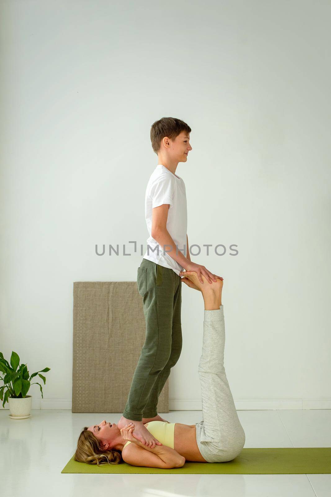 A guy in sportswear is doing yoga, standing on his hands, a slender woman lying on a sports mat. by Zakharova