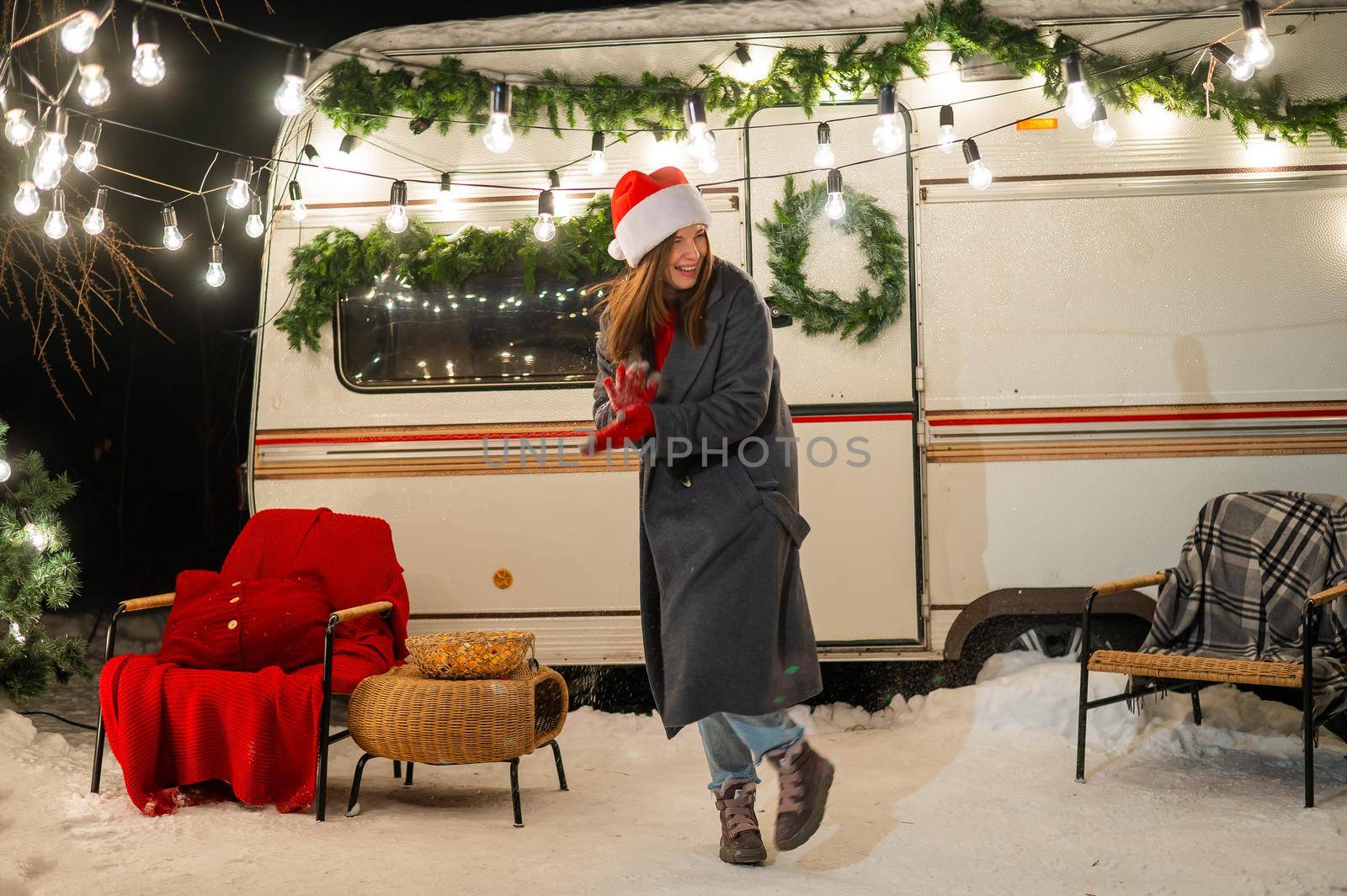 Caucasian woman in santa hat playing snowballs at camper. by mrwed54