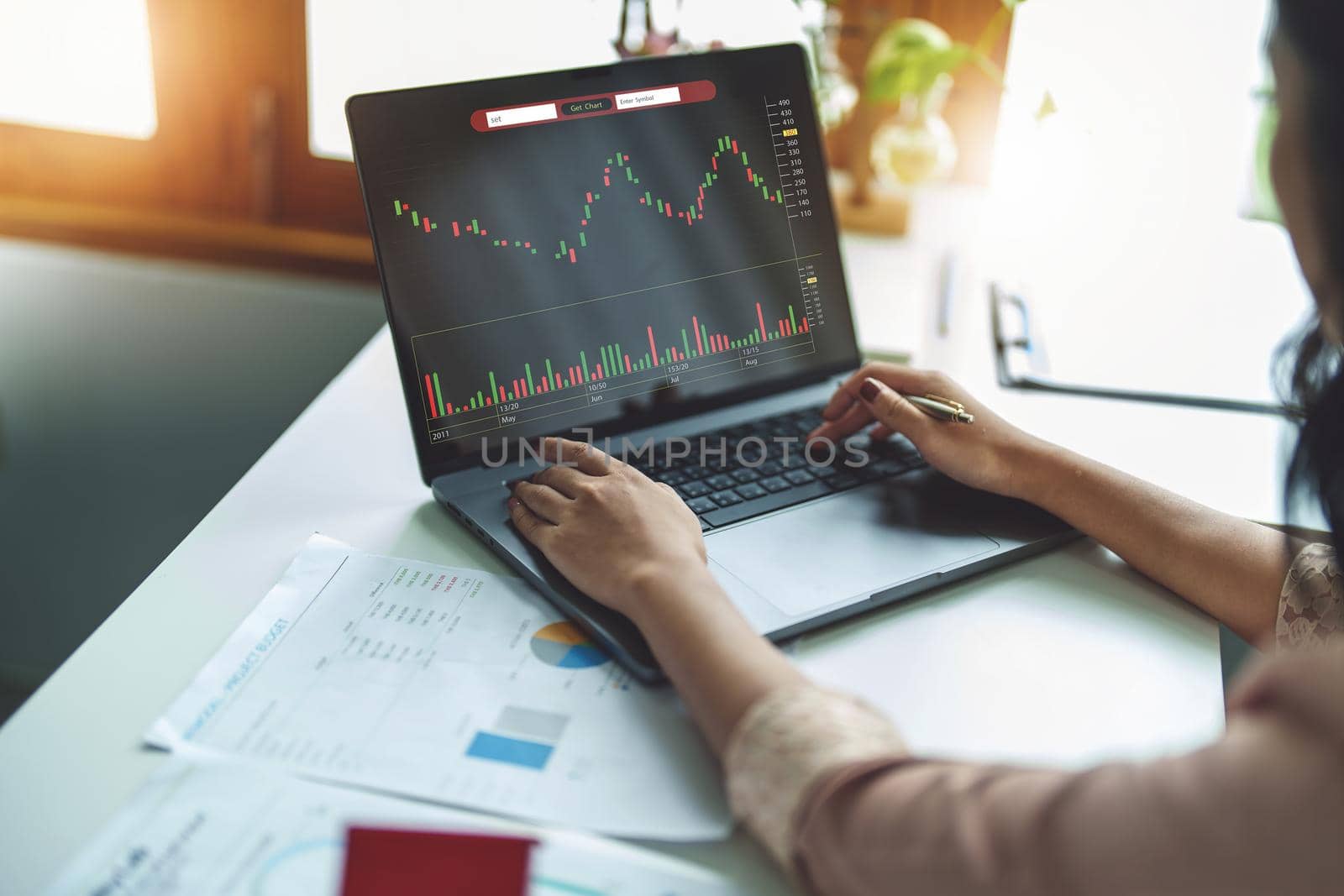 Financial and investment planning concept, female businesswoman using computer to analyze charts to find entry points on a trading board. through digital media via the internet. by Manastrong