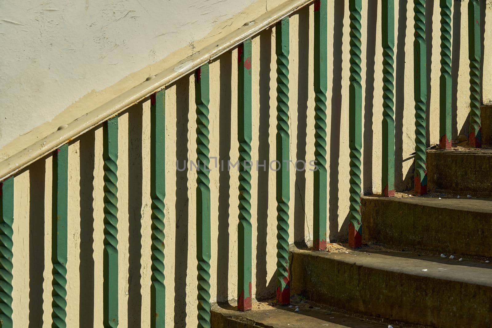 An abstract photograph of green metal railings and concrete steps