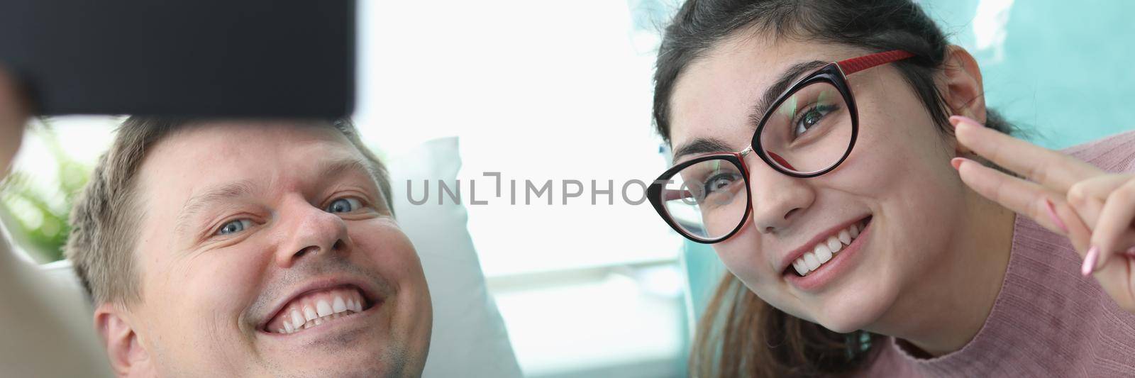 Portrait of smiling young woman and hospital patient taking selfie on mobile phone. Cheerful family picture. Modern clinic room for sick people. Medicine and recovery concept