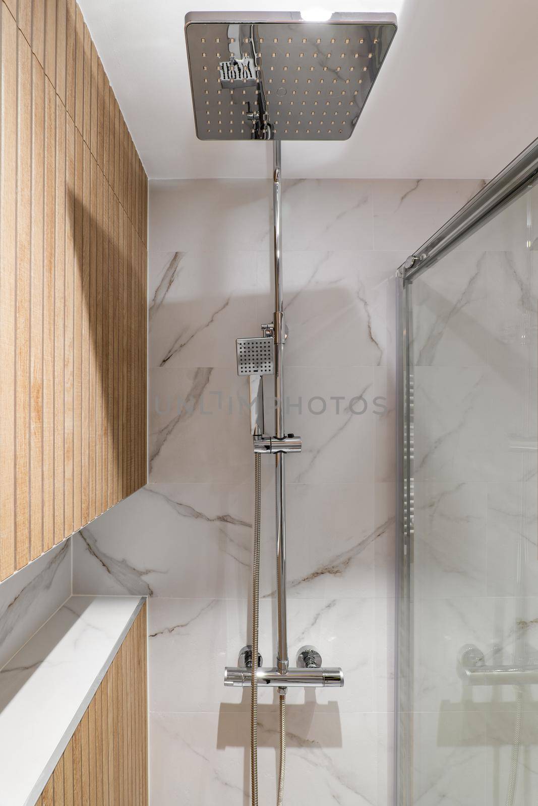 Big shower head and wooden finishing in interior of modern refurbished bathroom