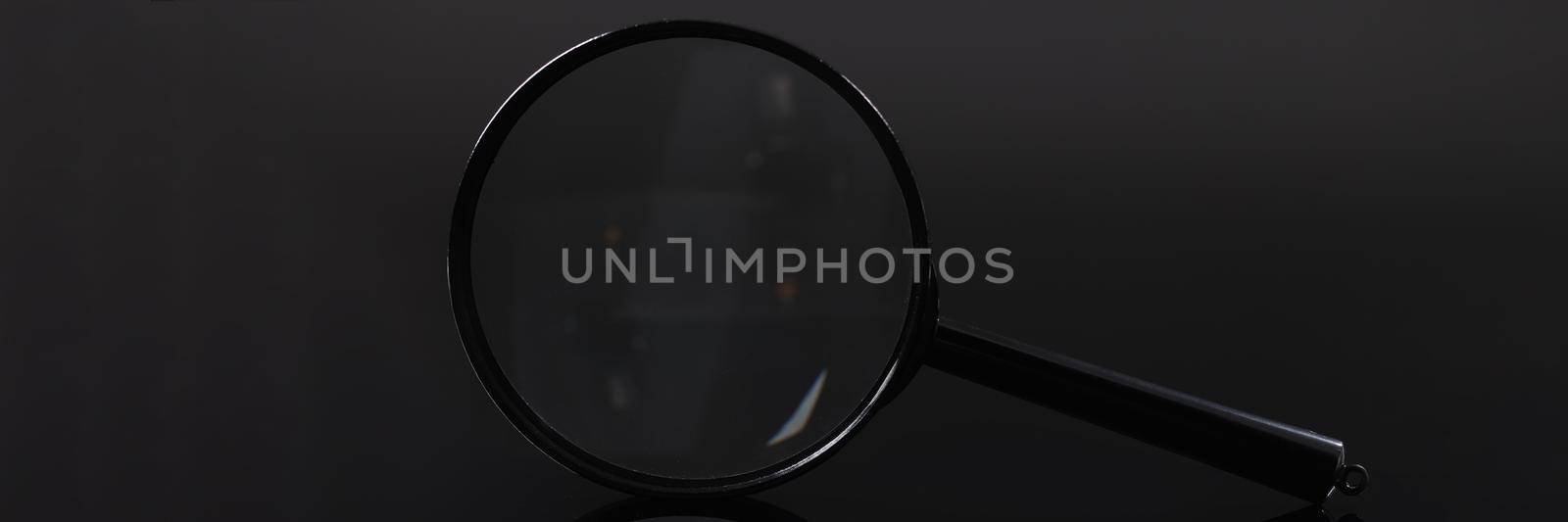Closeup of magnifying glass on black background. Hyperopia treatment concept