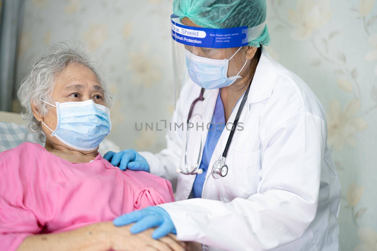 Doctor using stethoscope to checking Asian senior or elderly old lady woman patient wearing a face mask in hospital for protect infection Covid-19 Coronavirus. by pamai