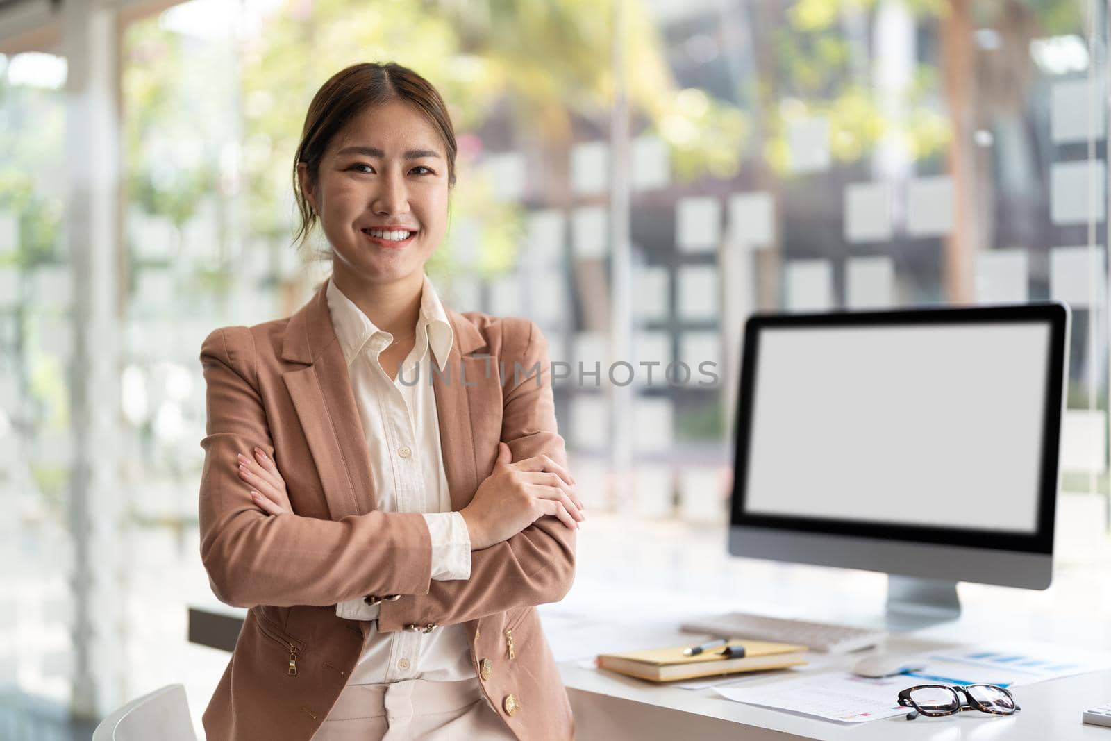portrait of young asian business woman standing arms crossed in modern office. by nateemee