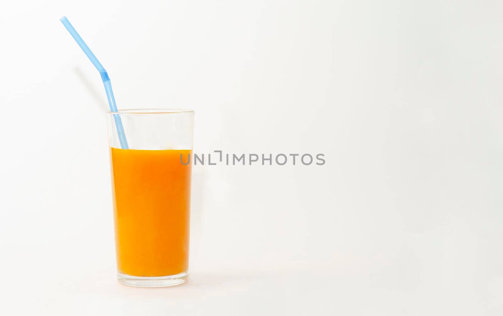 a glass of pumpkin juice with blue straw on white background by andre_dechapelle