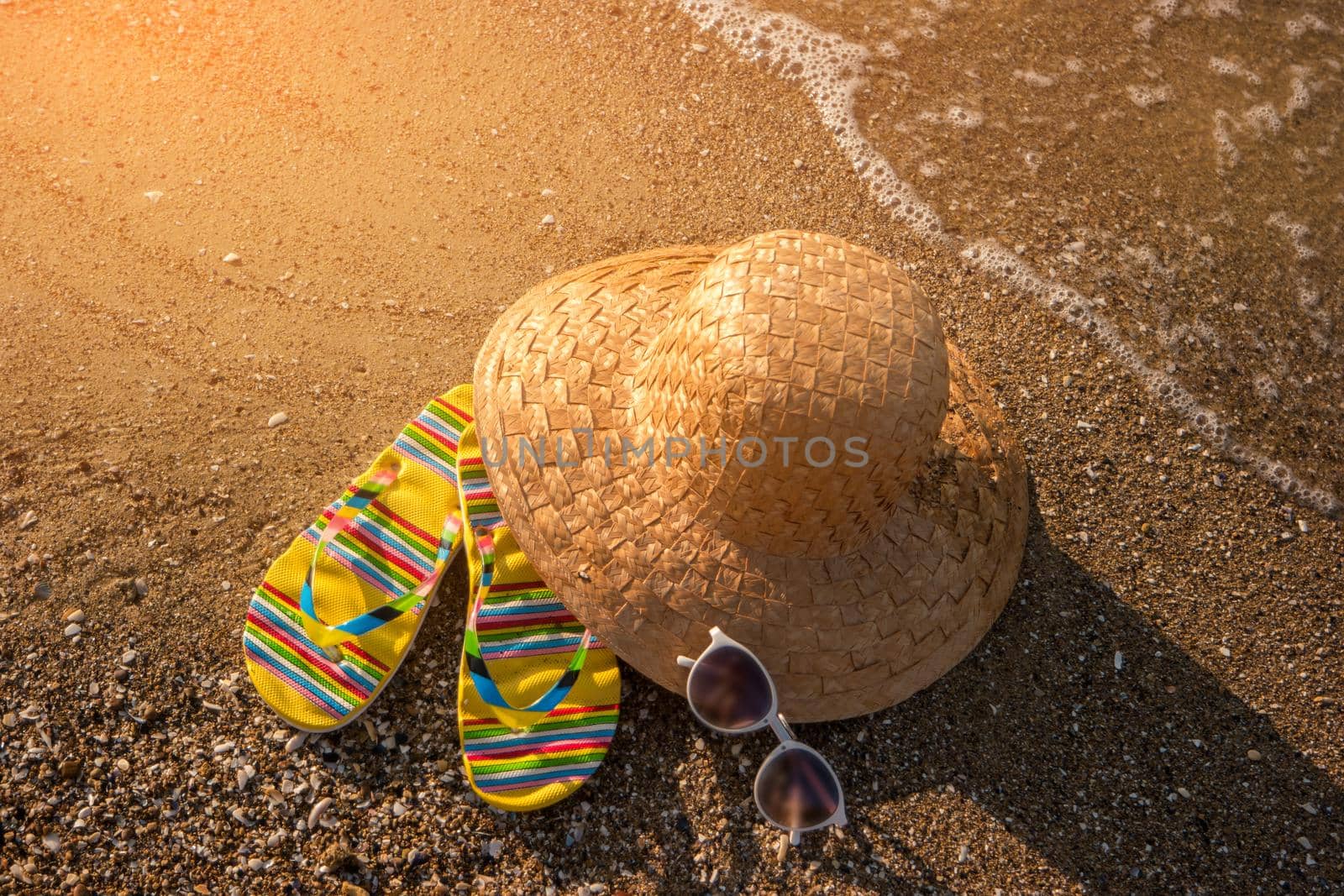 Wicker hat on the shore. Flip flops near water. Are you ready for summer. Bright sun and warm sea.